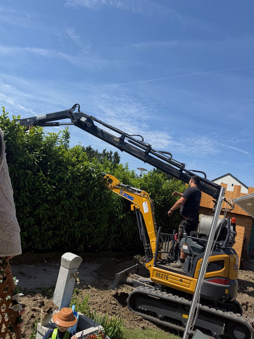 Minibagger mit ausgefahrenem Arm im Einsatz in einem Garten