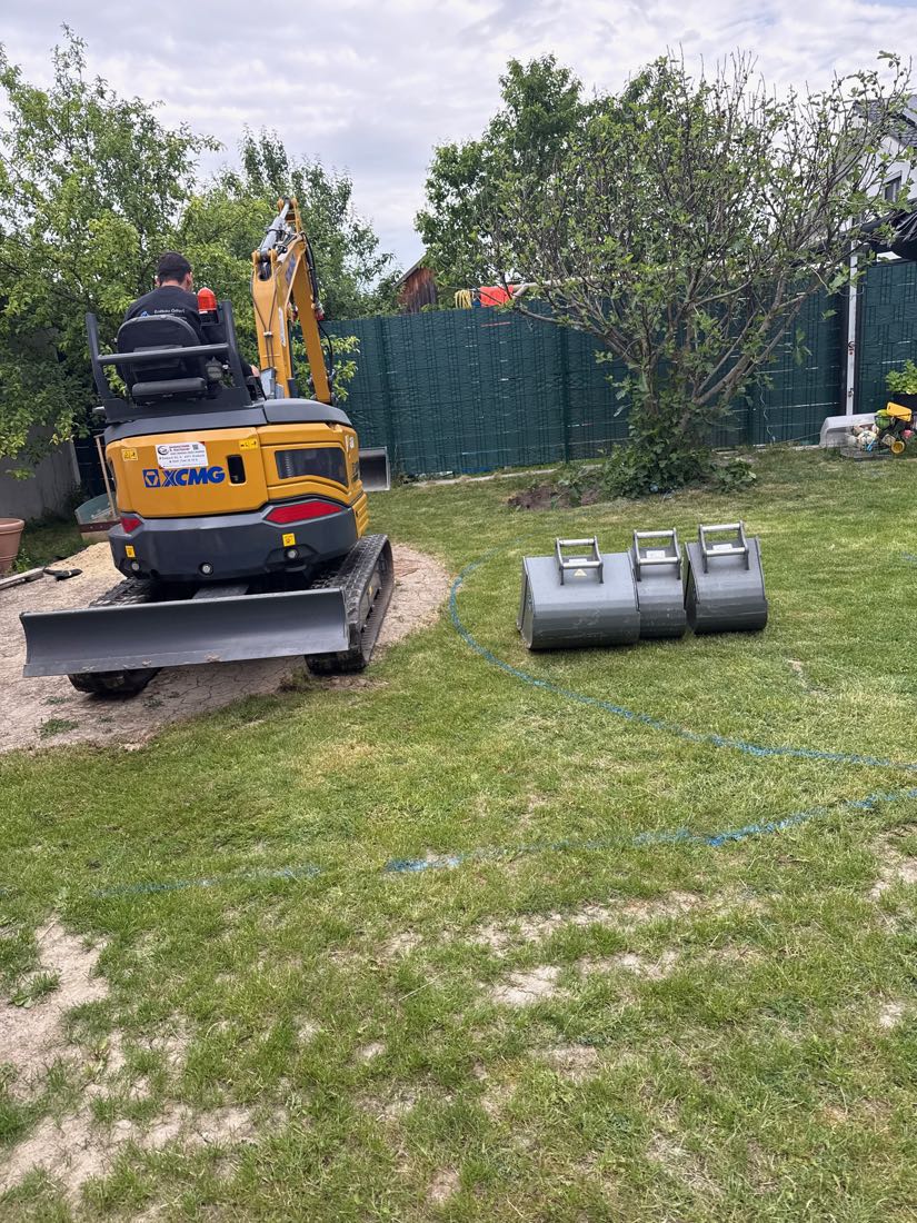 Minibagger mit Planierschild beim Einebnen einer Gartenfläche
